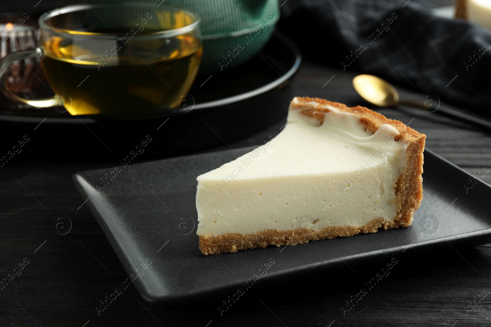 Photo of Piece of tasty vegan tofu cheesecake on black wooden table, closeup