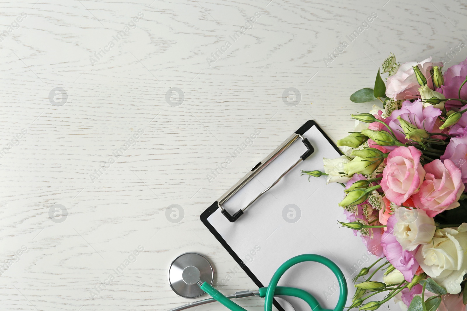 Photo of Flat lay composition with stethoscope and flowers on white wooden background, space for text. World health day