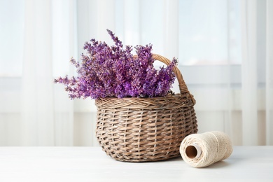 Photo of Wicker basket with lavender flowers on table indoors