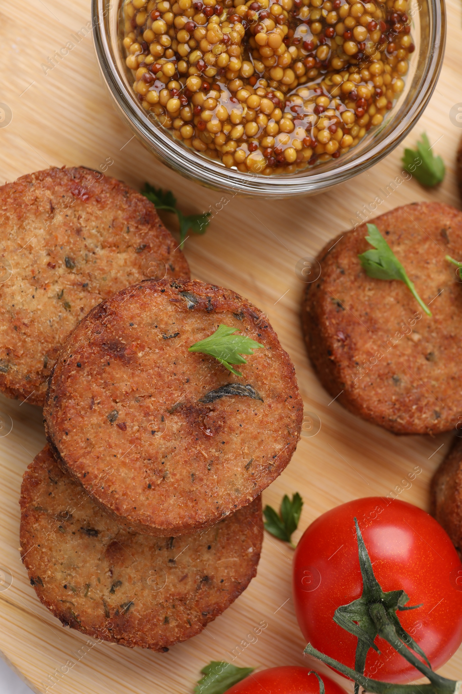 Photo of Tasty vegan cutlets, tomato and grain mustard on wooden table, flat lay