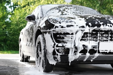 Photo of Auto covered with cleaning foam at outdoor car wash