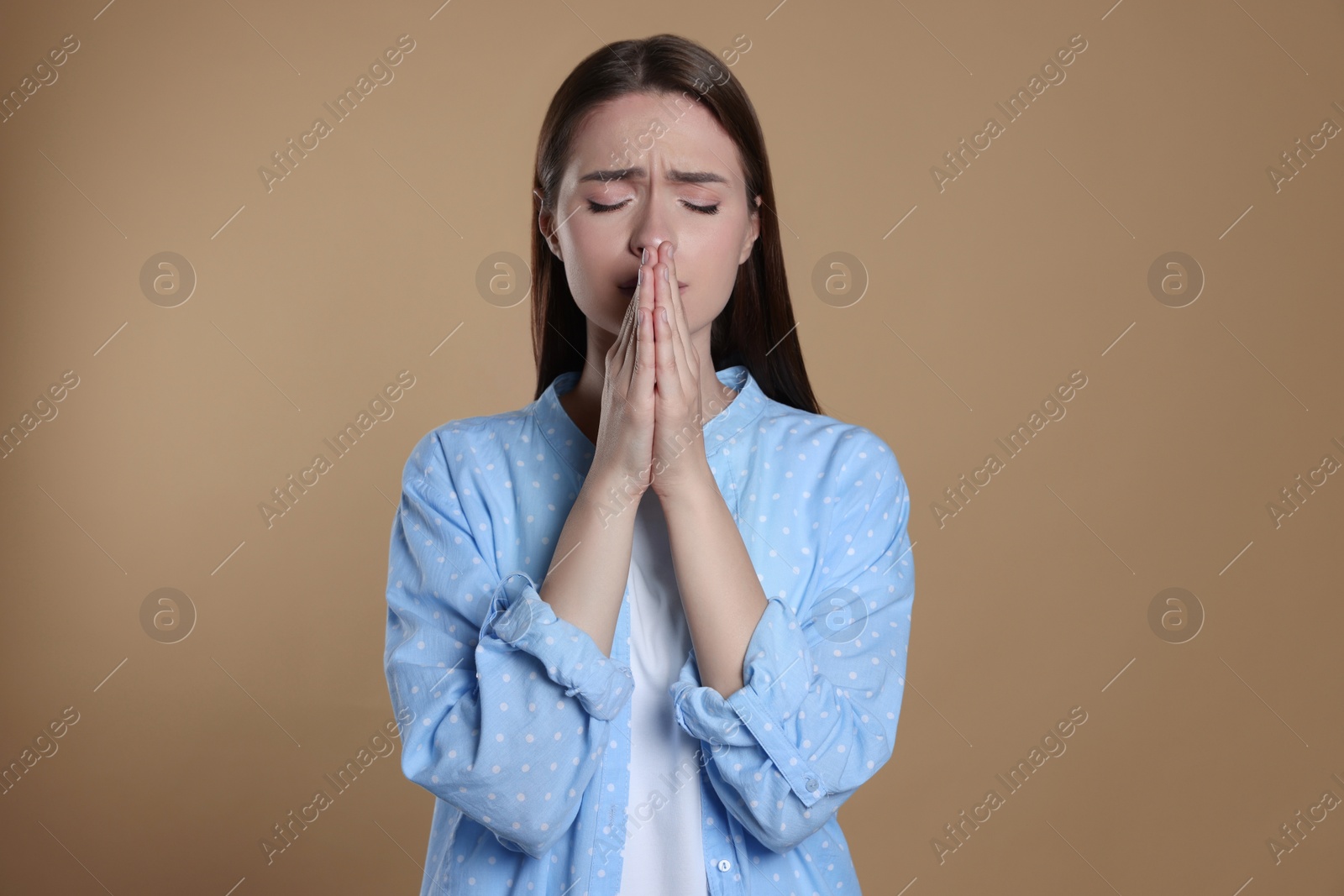 Photo of Woman with clasped hands praying on beige background