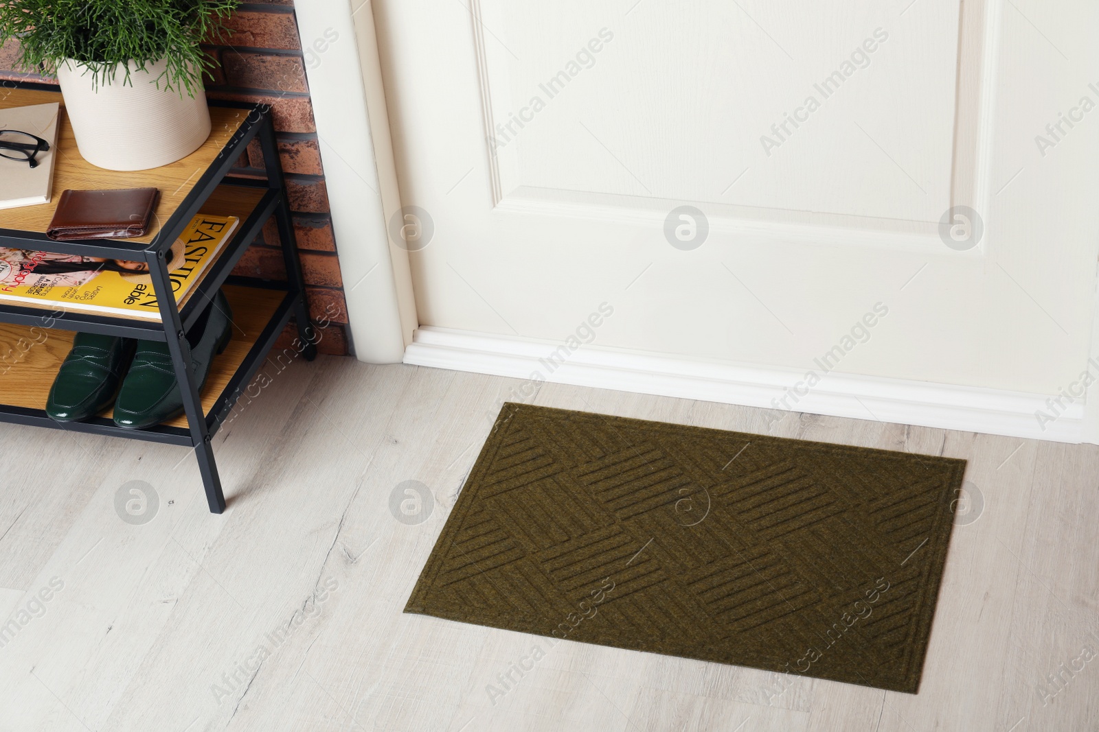 Photo of Dark olive door mat on wooden floor in hall