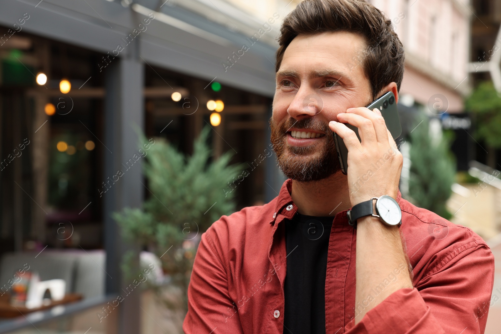 Photo of Handsome man talking on smartphone while walking outdoors, space for text