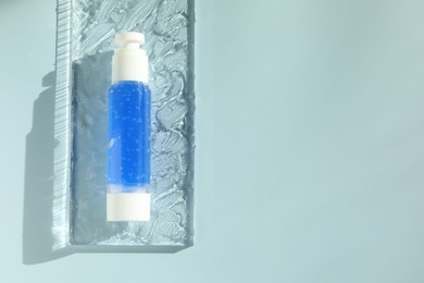 Bottle of cosmetic product on light blue background, top view. Space for text