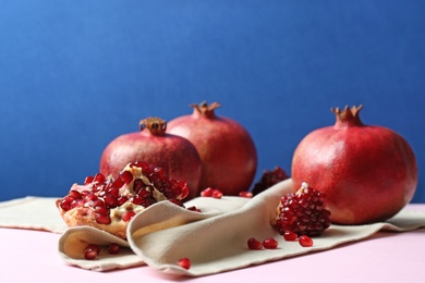 Photo of Ripe pomegranates on table against color background