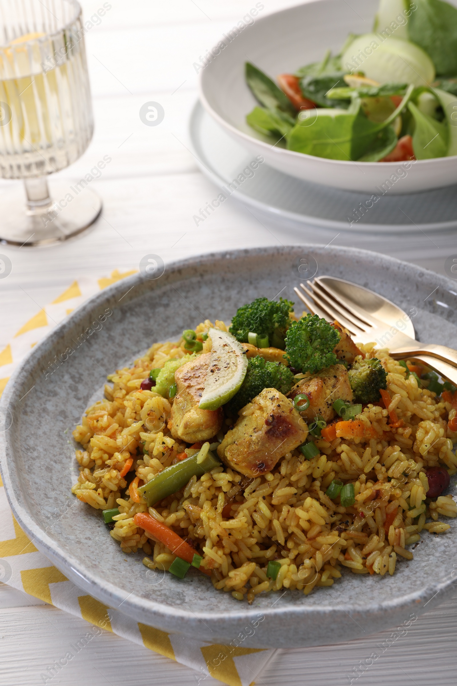 Photo of Tasty rice with meat and vegetables in plate served on white wooden table