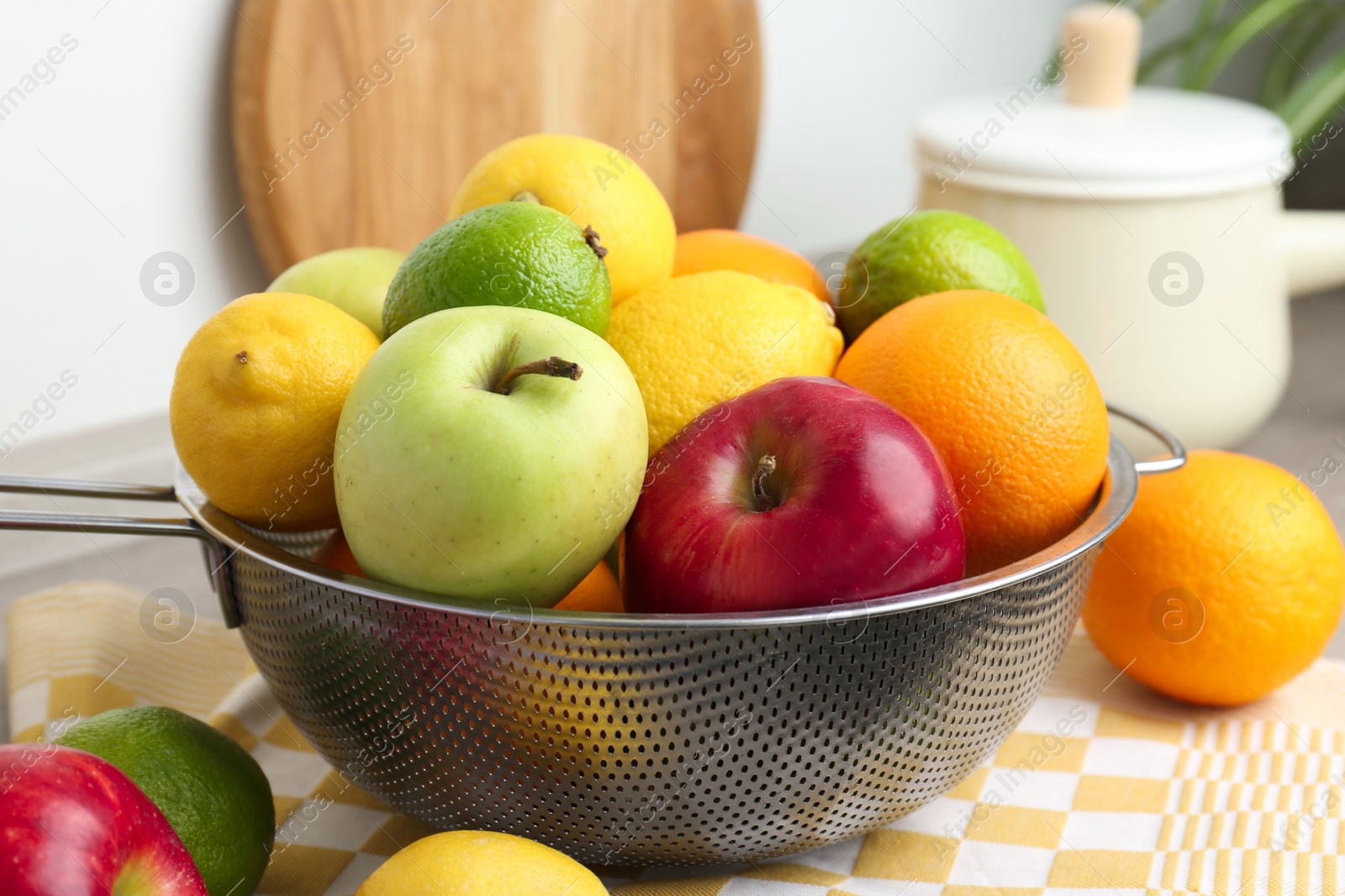 Photo of Metal colander with different fruits on table, closeup