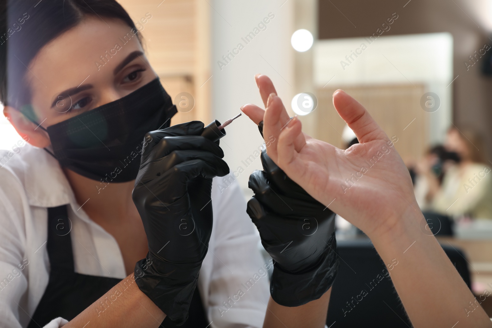 Photo of Professional manicurist working with client in salon, closeup. Beauty services during Coronavirus quarantine