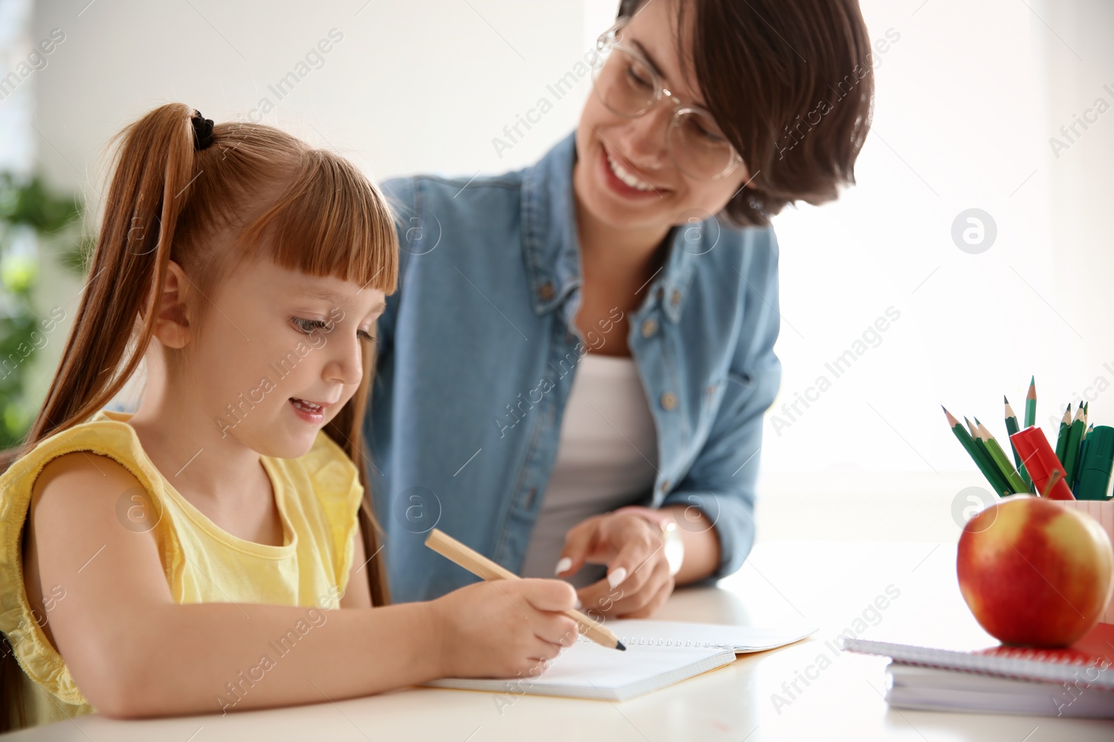 Photo of Female teacher helping child with assignment at school