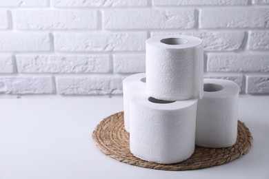 Photo of Toilet paper rolls on white table against brick wall, space for text
