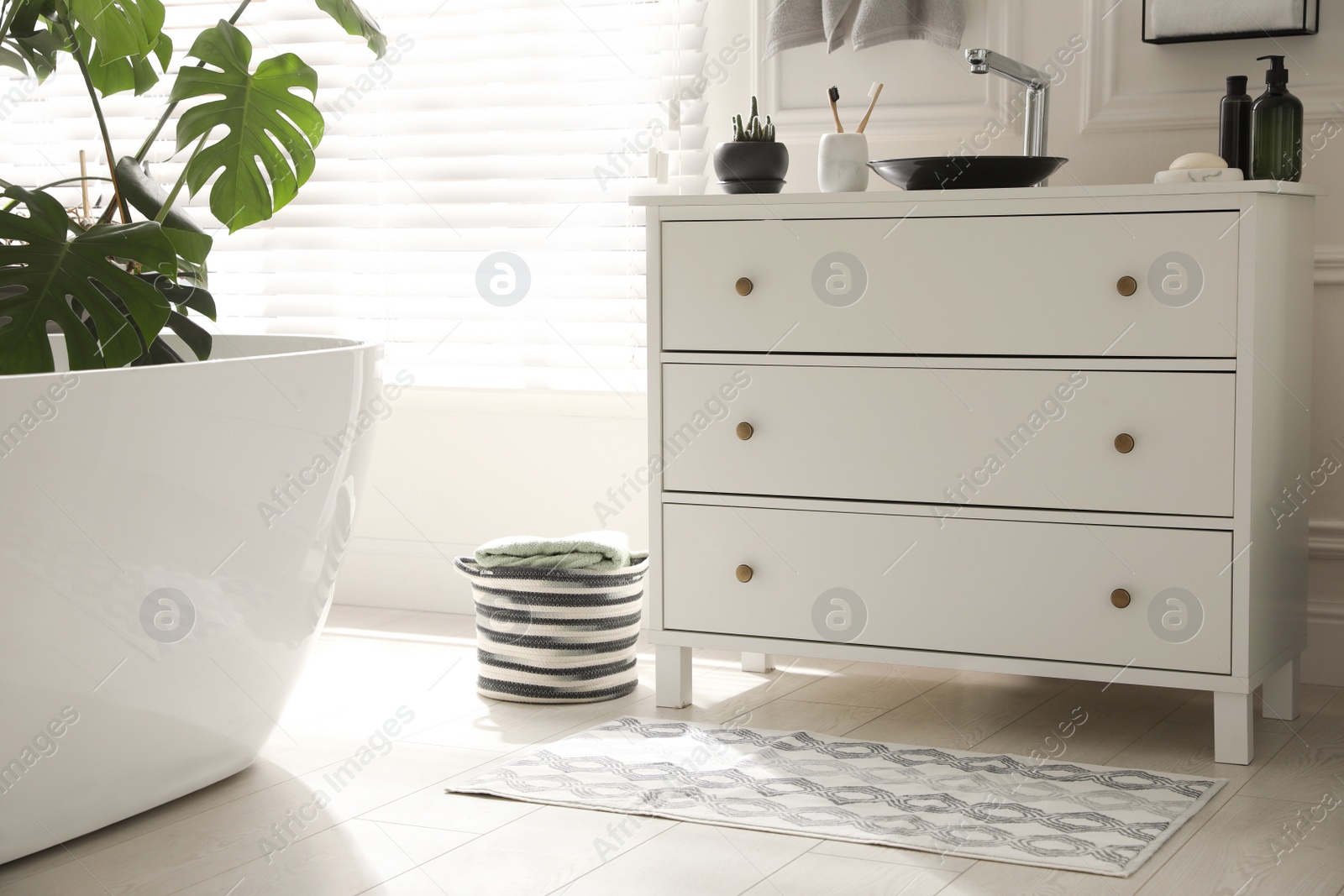 Photo of Stylish mat with pattern near chest of drawers in bathroom