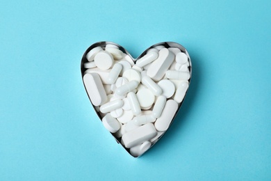 Photo of Heart made of pills on color background, top view. Cardiology concept