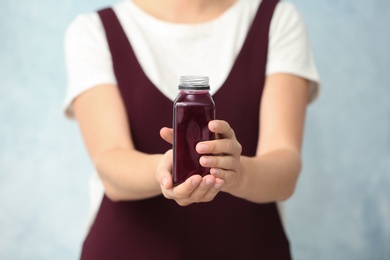 Photo of Woman with bottle of beet smoothie on light background, closeup