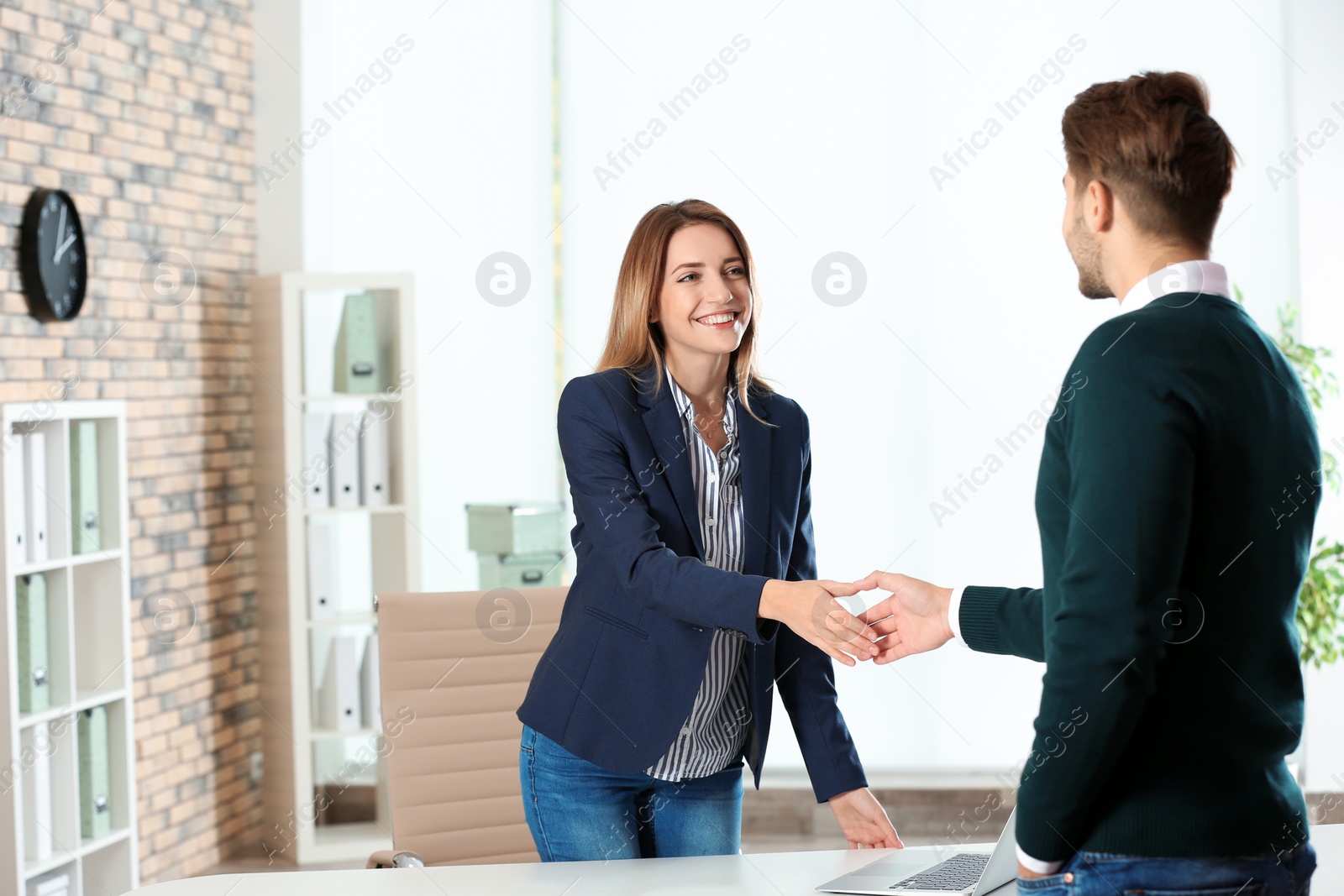 Photo of Human resources manager shaking hands with applicant before job interview in office