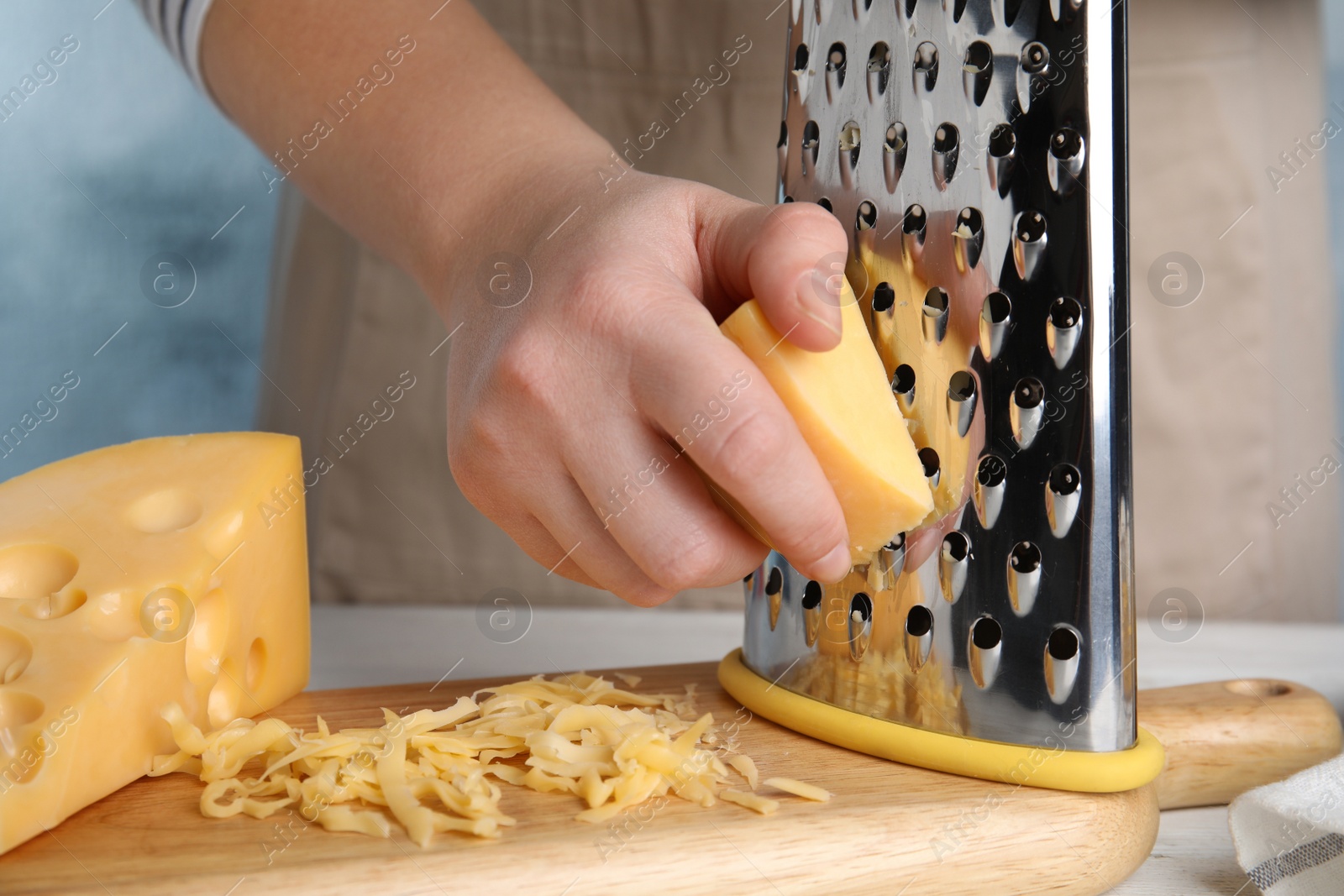 Photo of Woman grating fresh cheese at table, closeup