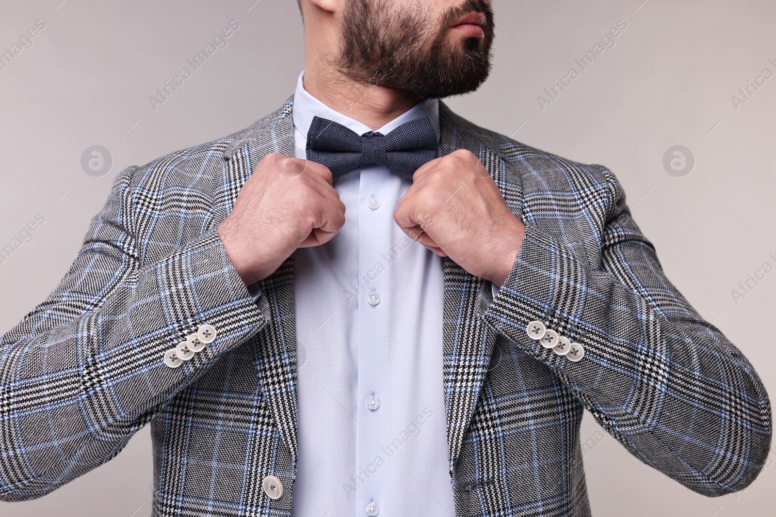 Photo of Man adjusting bow tie on grey background, closeup