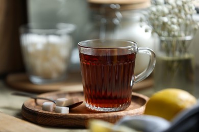 Photo of Glass cup with delicious tea and sugar on table, closeup