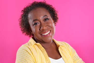 Portrait of happy African-American woman on pink background