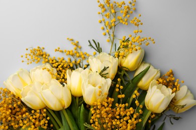 Bouquet with beautiful tulips and mimosa flowers on light grey background, top view