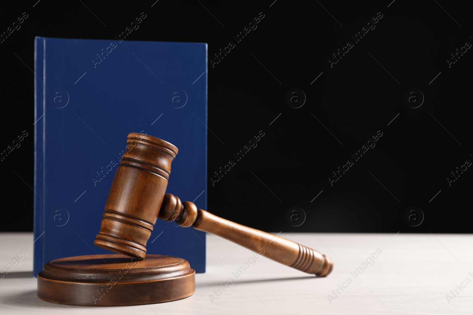 Photo of Judge's gavel and book on white table against black background, space for text. Criminal law concept