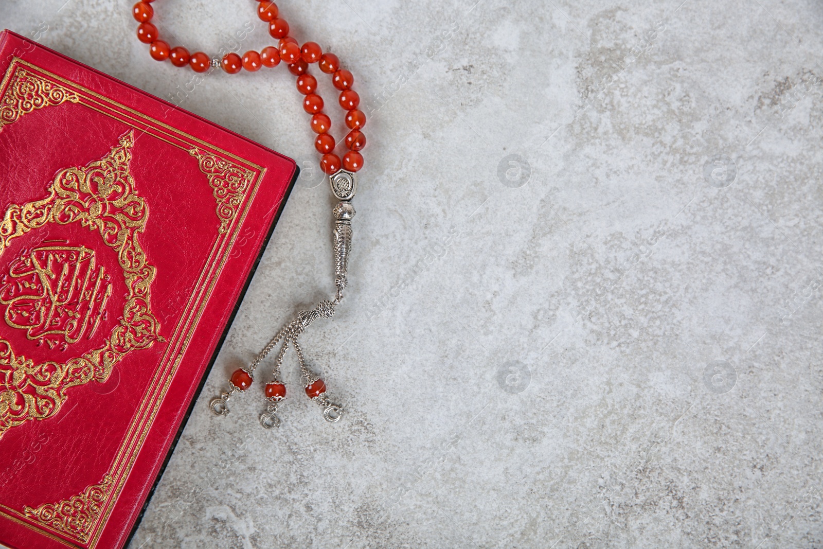 Photo of Muslim prayer beads, Quran and space for text on grey background, top view