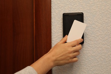 Photo of Woman opening magnetic door lock with key card indoors, closeup