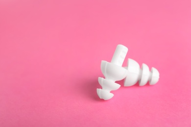 Photo of Pair of white ear plugs on pink background. Space for text