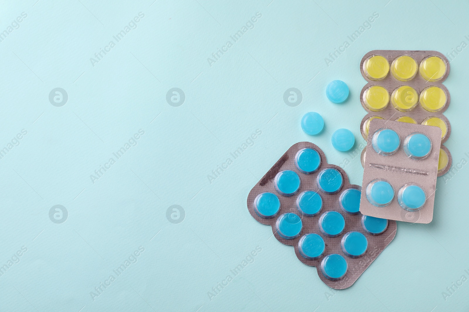 Photo of Colorful cough drops on light blue background, flat lay. Space for text