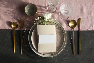 Photo of Stylish table setting. Dishes, cutlery, blank card and floral decor, flat lay