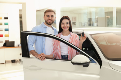 Photo of Happy couple near new car in dealership
