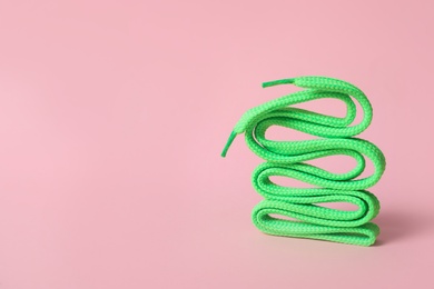Photo of Mint shoe lace on light pink background. Space for text