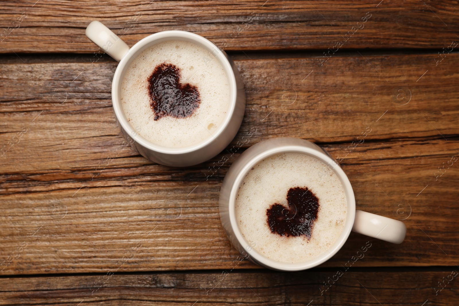 Photo of Cups of aromatic coffee with heart shaped decoration on wooden table, flat lay