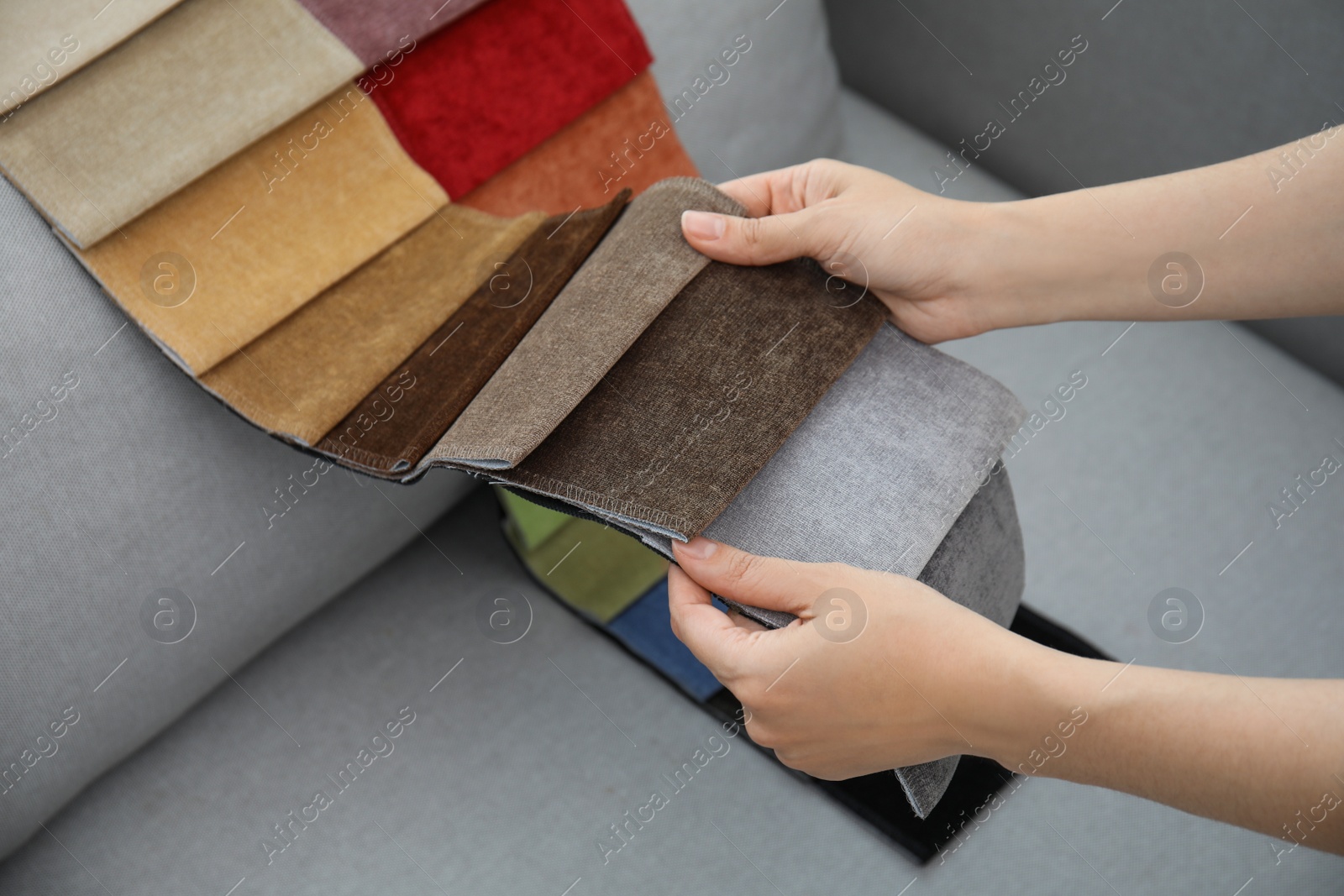 Photo of Woman choosing fabric among colorful samples on grey sofa, closeup