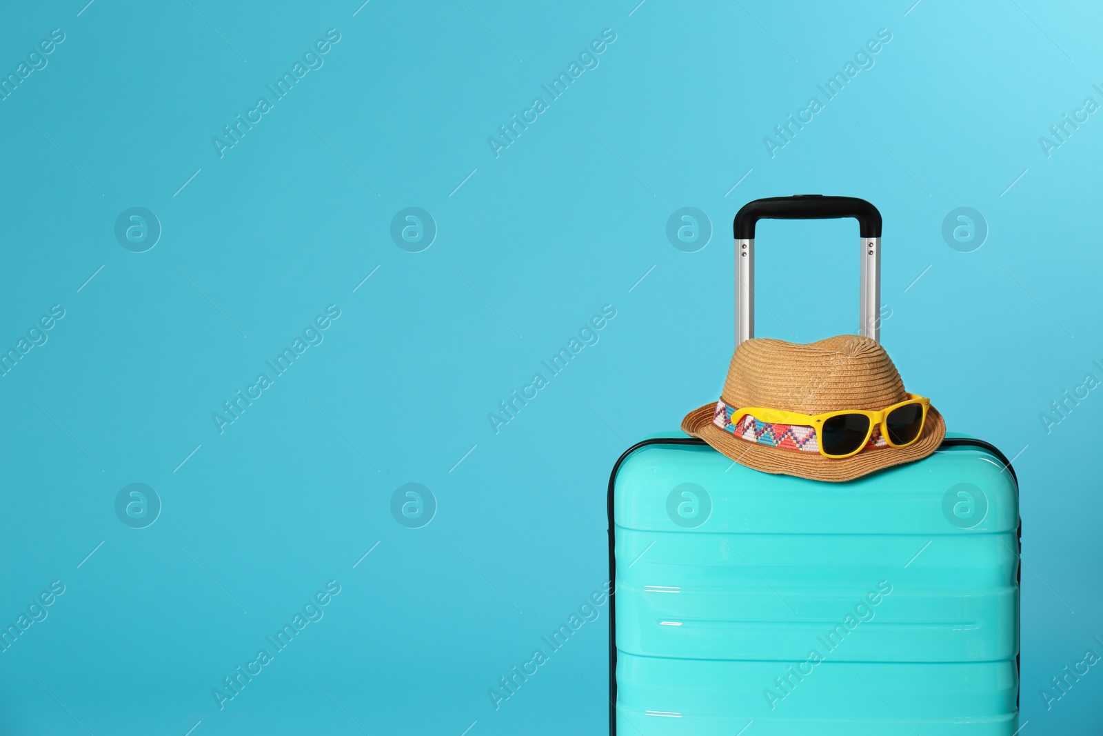 Photo of Stylish suitcase with hat and sunglasses on color background. Space for text