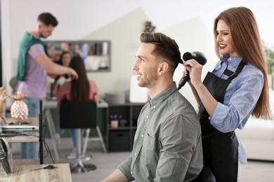 Photo of Professional hairdresser working with client in beauty salon