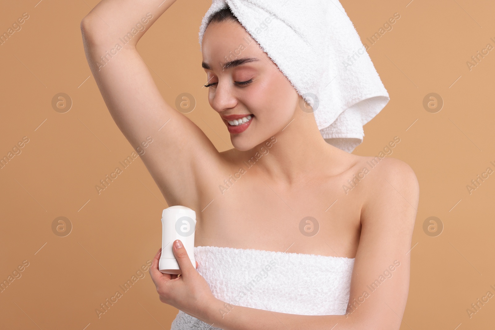 Photo of Beautiful woman applying deodorant on beige background