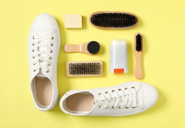 Photo of Flat lay composition with stylish footwear and shoe care accessories on yellow background