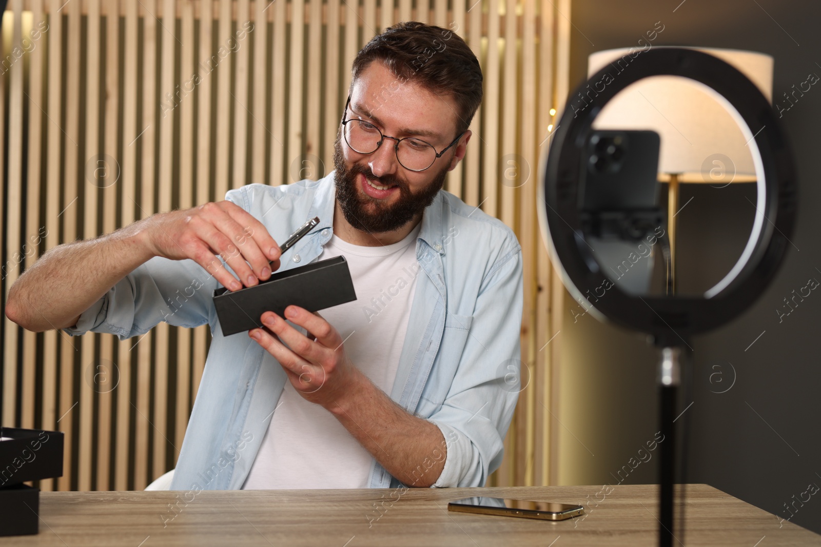 Photo of Smiling technology blogger recording video review about smartphones at home