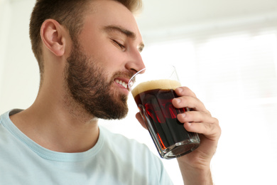 Handsome man with cold kvass indoors. Traditional Russian summer drink