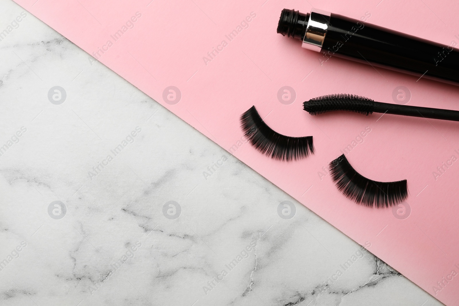 Photo of Mascara and artificial eyelashes on table. Space for text