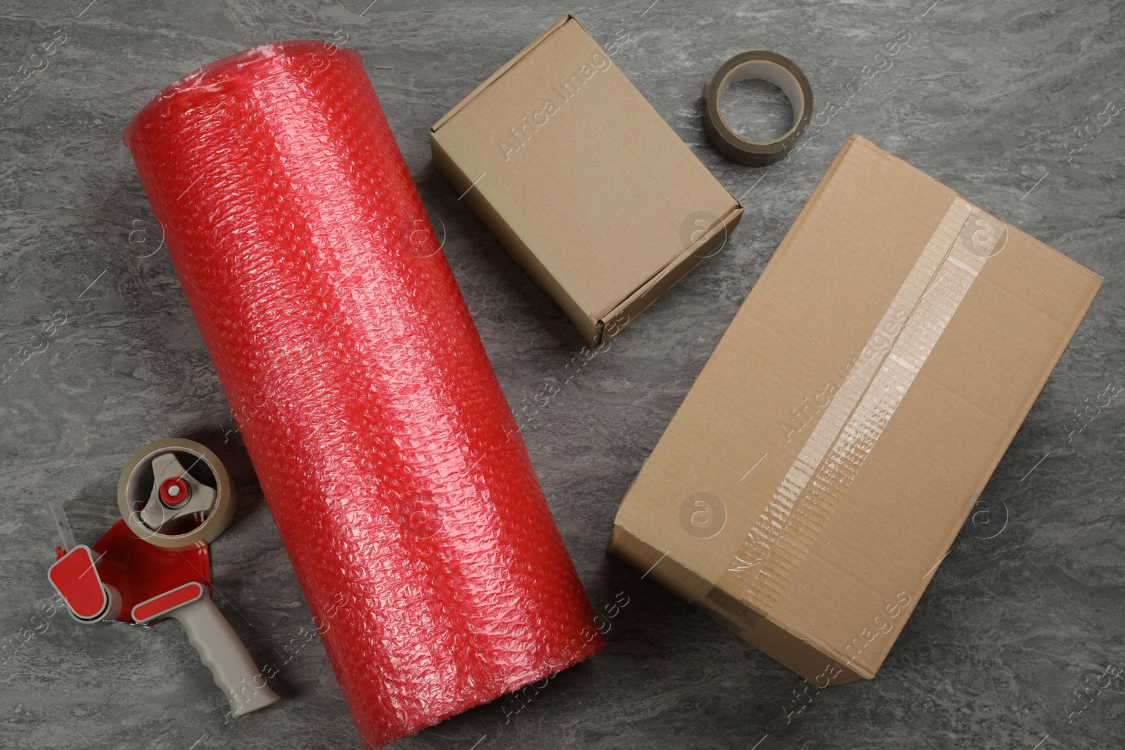 Photo of Flat lay composition with bubble wrap roll on grey background