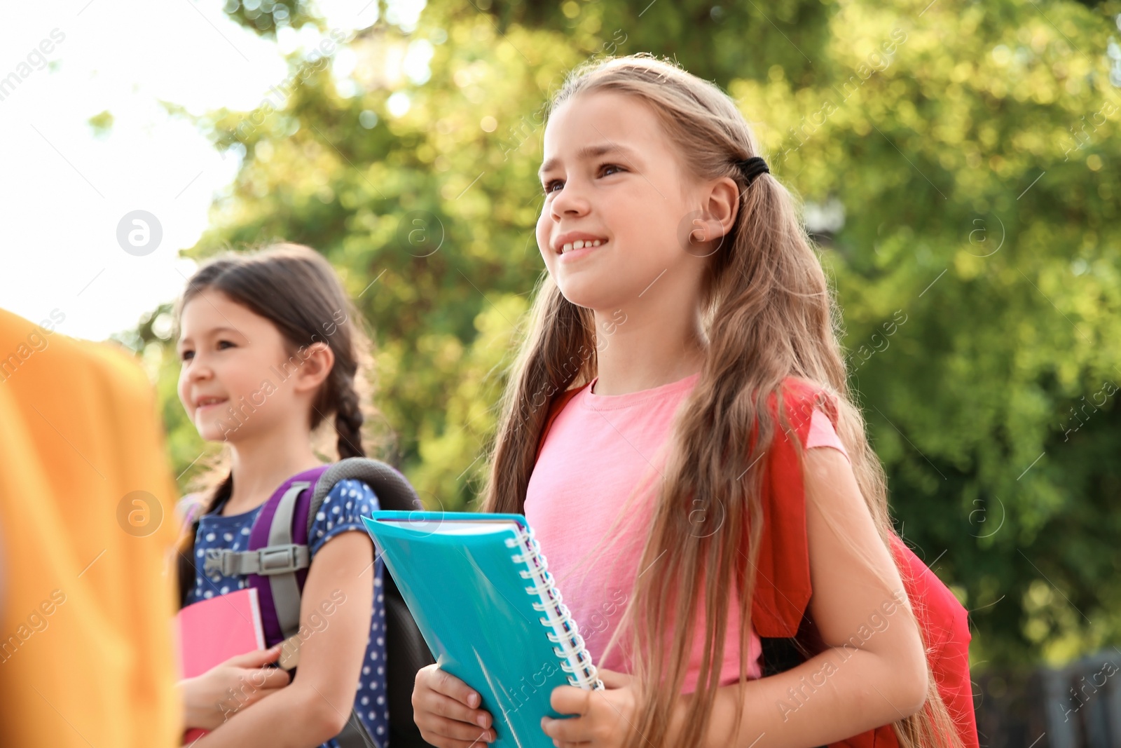 Photo of Cute little children with backpacks and notebooks outdoors. Elementary school