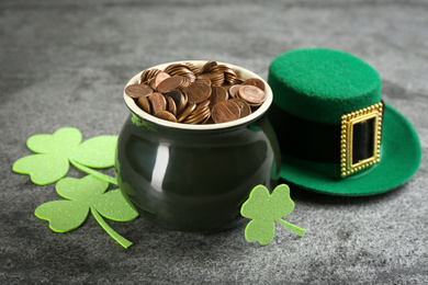 Photo of Pot of gold coins, hat and clover leaves on grey stone table. St. Patrick's Day celebration