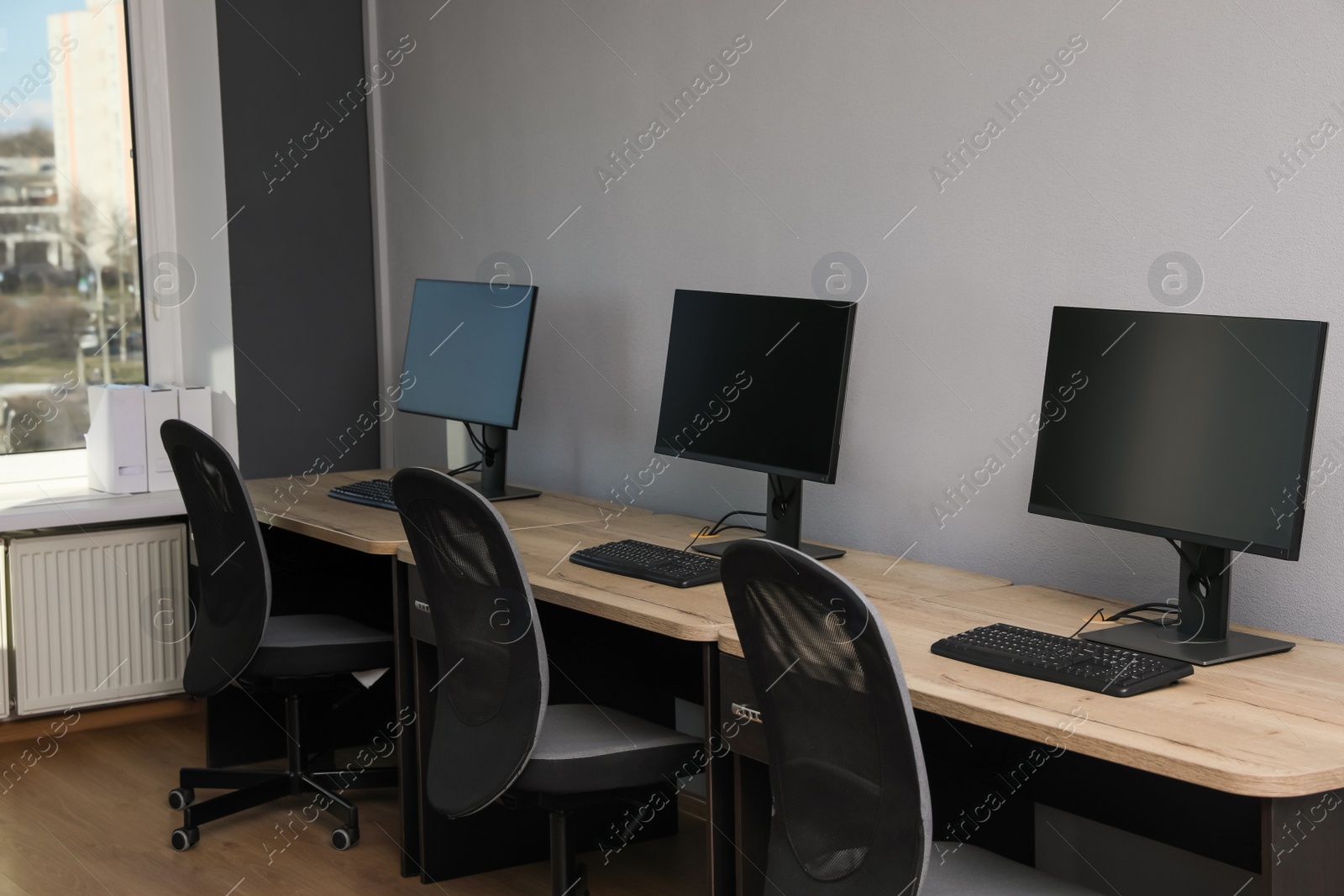 Photo of Open office interior. Modern workplaces with computers near light grey wall