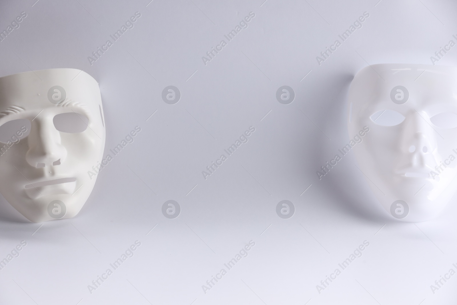 Photo of Plastic face masks on white background, space for text. Theatrical performance