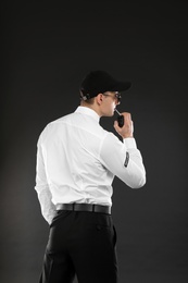 Male security guard using portable radio transmitter on dark background