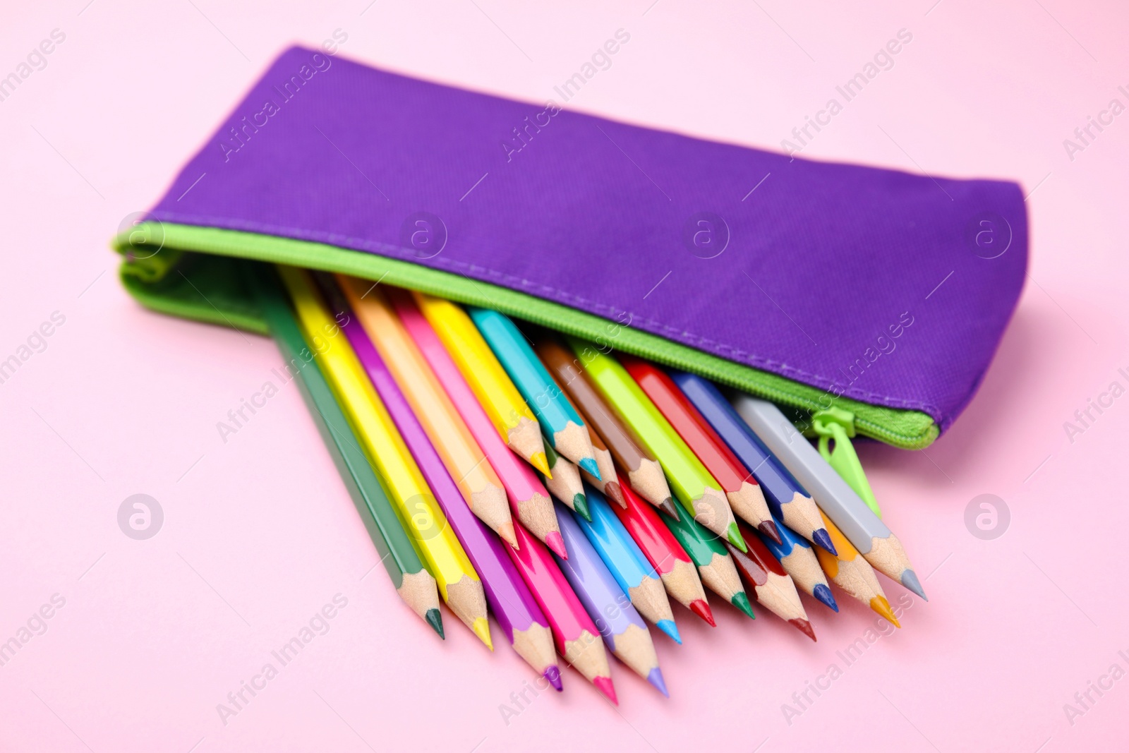Photo of Many colorful pencils in pencil case on pink background, closeup