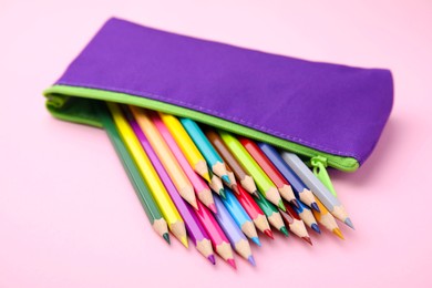 Photo of Many colorful pencils in pencil case on pink background, closeup