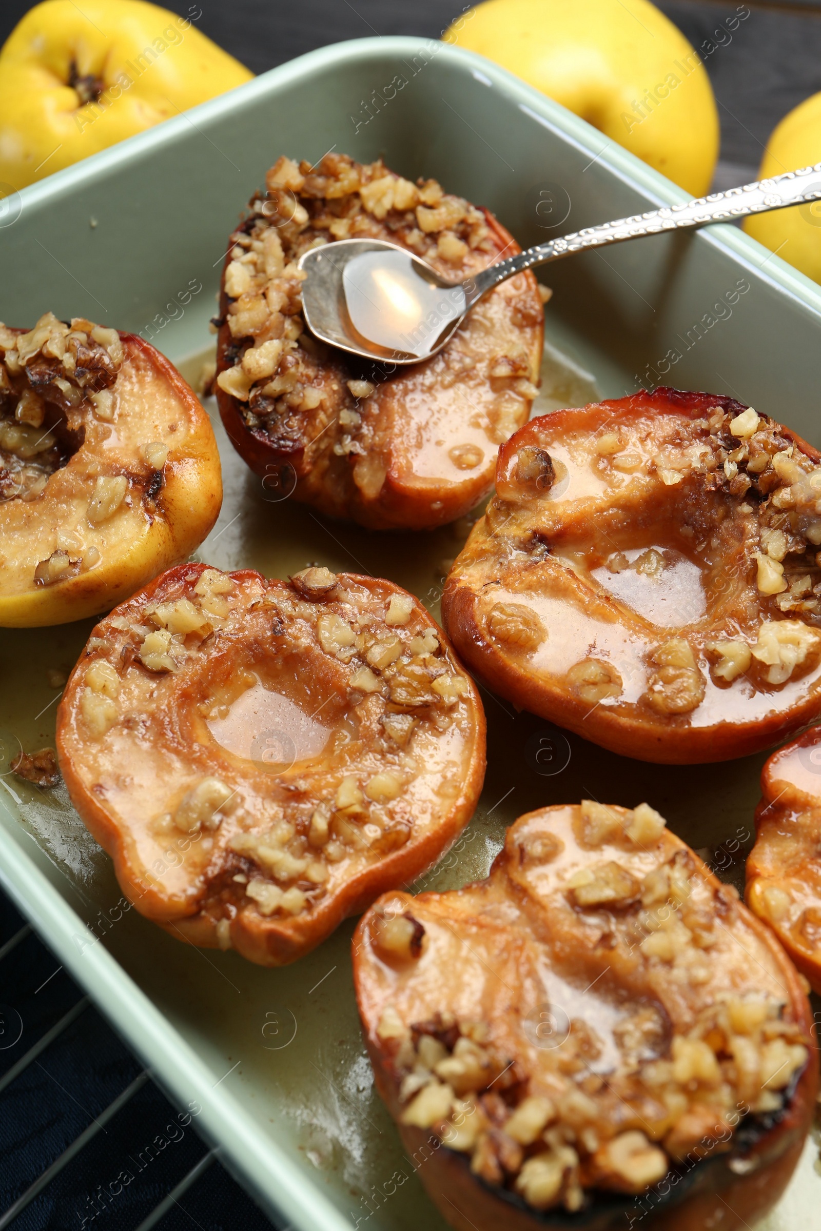 Photo of Tasty baked quinces with nuts and honey in dish on grid, closeup